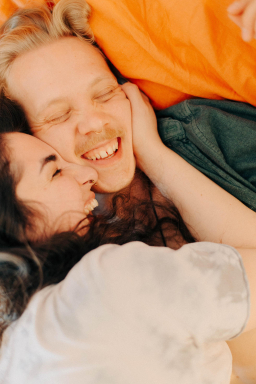 Lachendes Paar liegt gemeinsam im Bett